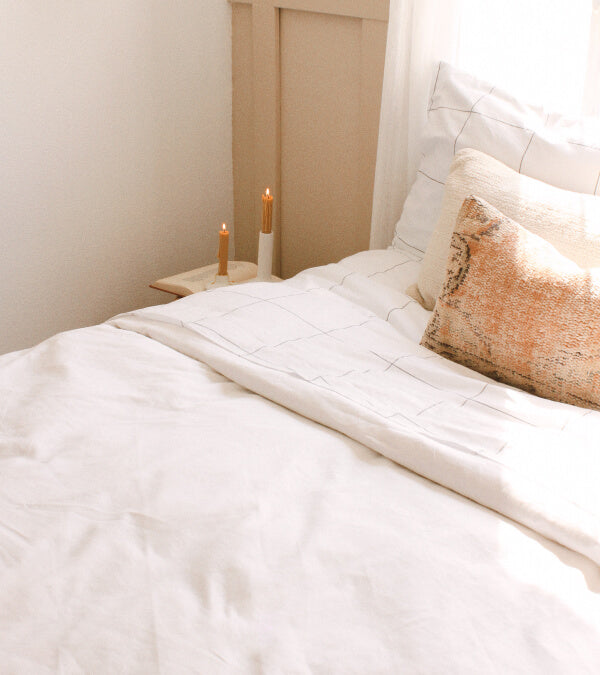 Bed made up in rumpled windowpane and white sheets.