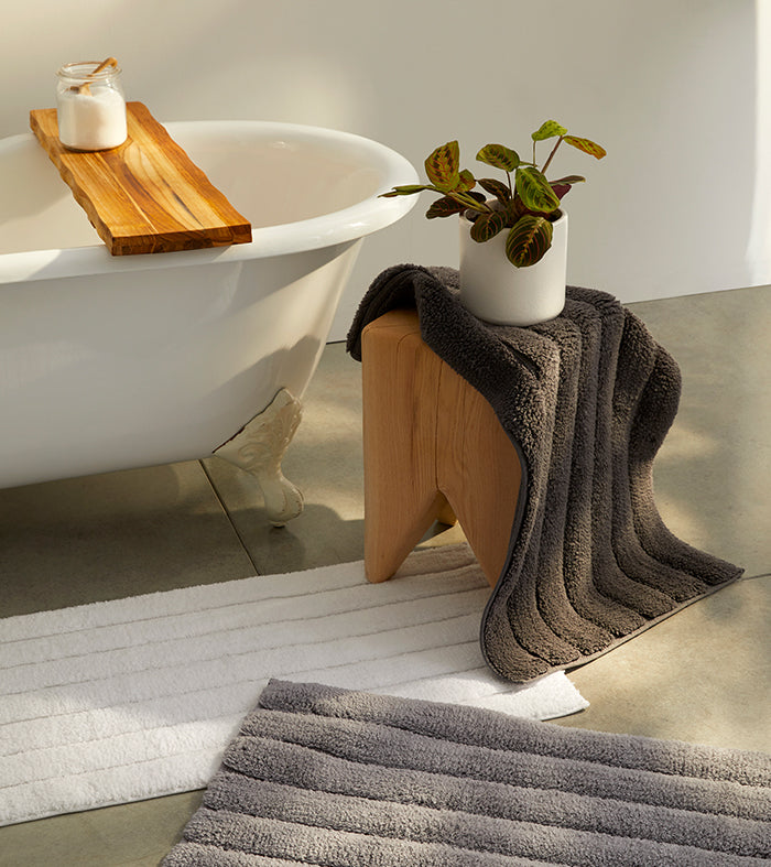 White and graphite bath rugs draped around a claw foot tub